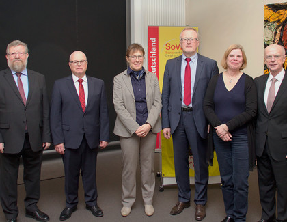 Gruppenbild mit Damen und Herren in Anzügen vor einem SoVD-Aufsteller.