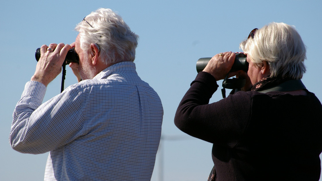 Foto älteres Ehepaar schaut mit Fernglas in die Ferne,