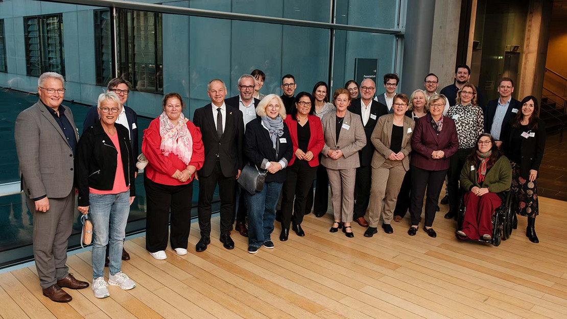 Gruppenfoto mit etwa 20 Personen vor einer Fensterscheibe