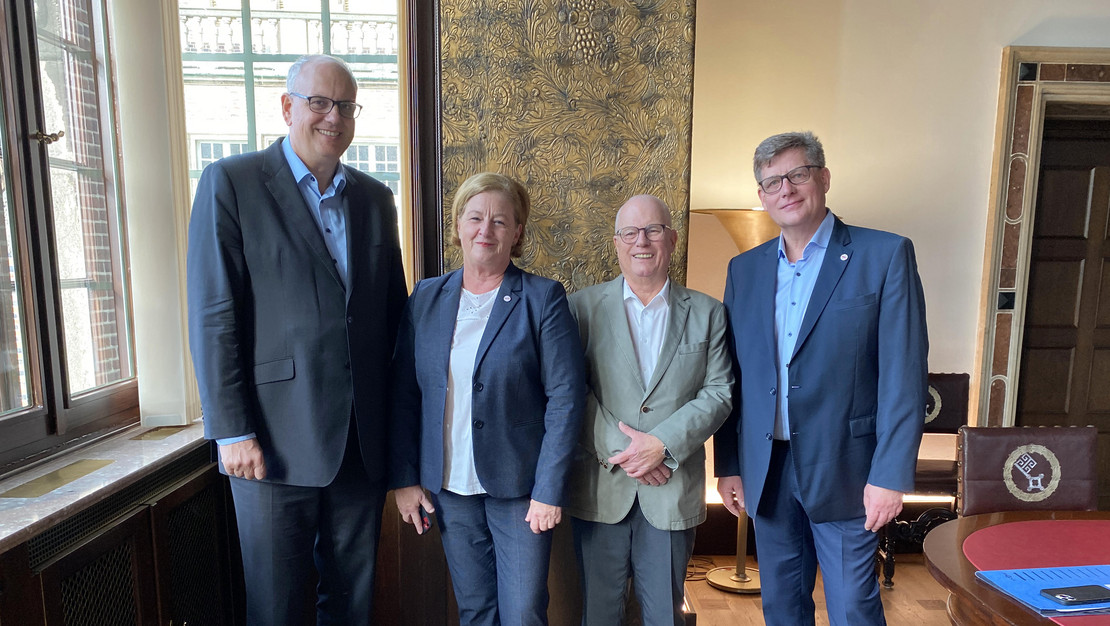 Im Rathaus stehen vor einem goldfarbenen Paravent Bremens Bürgermeister Dr. Andreas Bovenschulte, Michaela Engelmeier, 1. Landesvorsitzender Joachim Wittrien und Michael Meder (von links). 