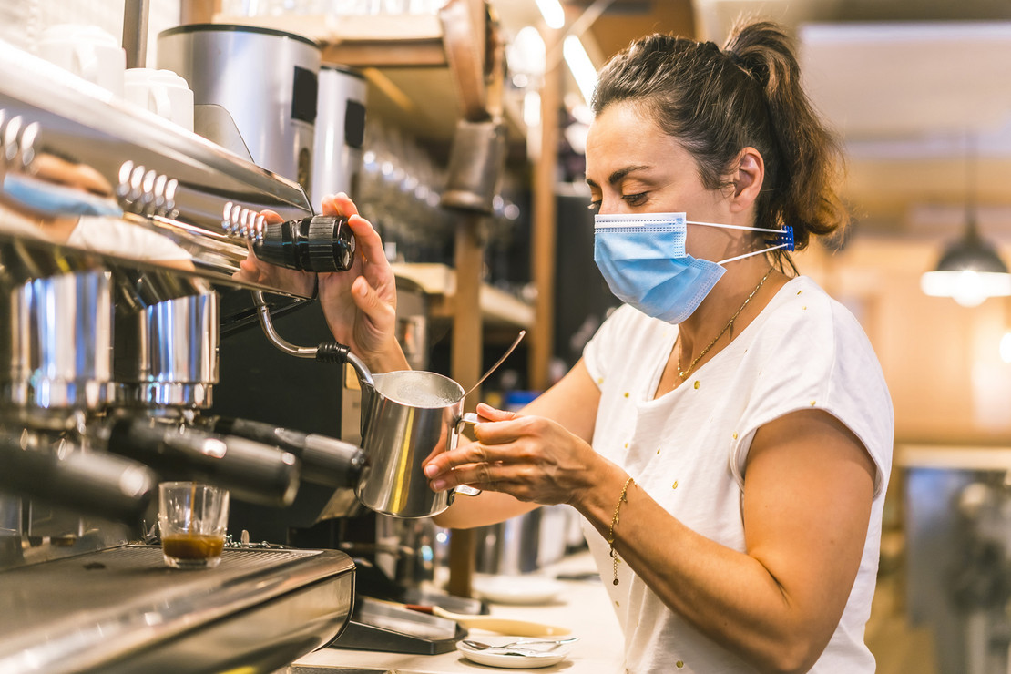 Frau in einer Bar bereitet Kaffee zu. 